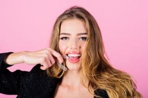 Teeth retainer for improving bite. Teeth care. Sensative woman holds teeth retainer. Mobile orthodontic appliance. Close-up of woman holds transparent teeth aligner.