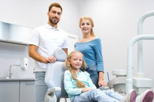 happy young family looking at camera at dentist office
