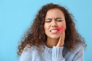 African-American woman suffering from tooth ache on color background